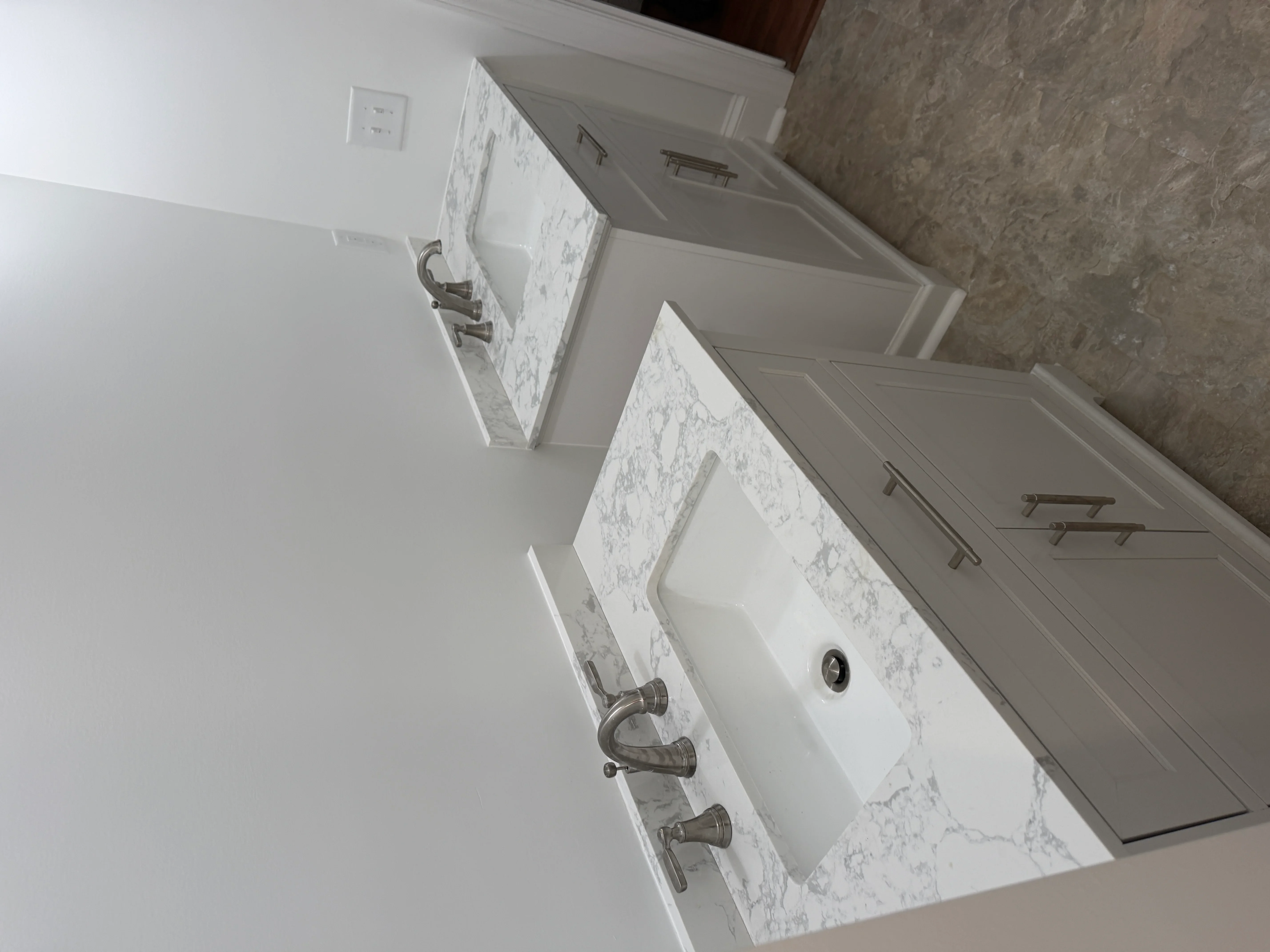 Dual white marble vanity with brushed nickel wall-mounted faucets and soft-close cabinets