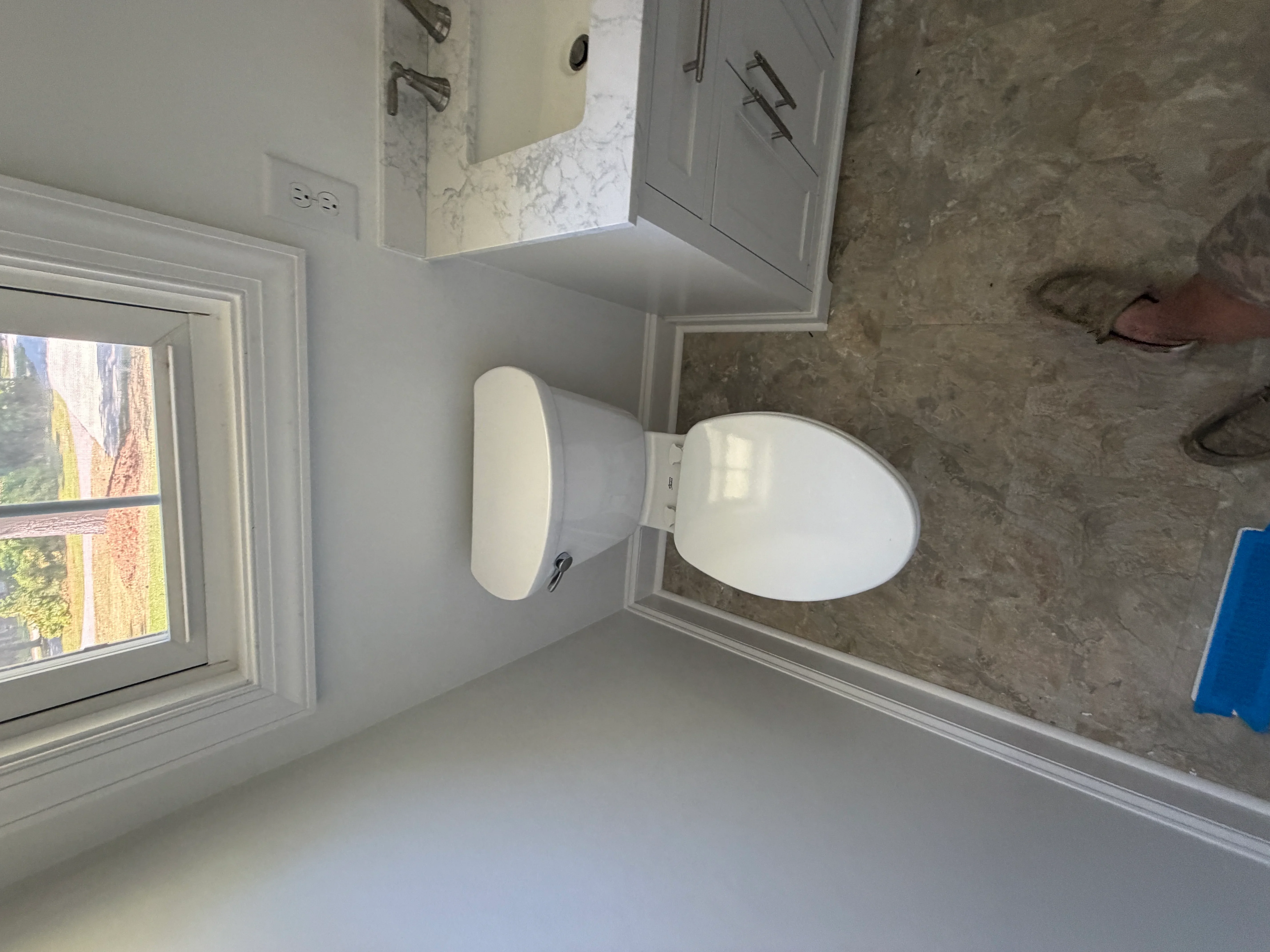 White ceramic toilet and pedestal sink with chrome hardware in newly finished bathroom with marble tile