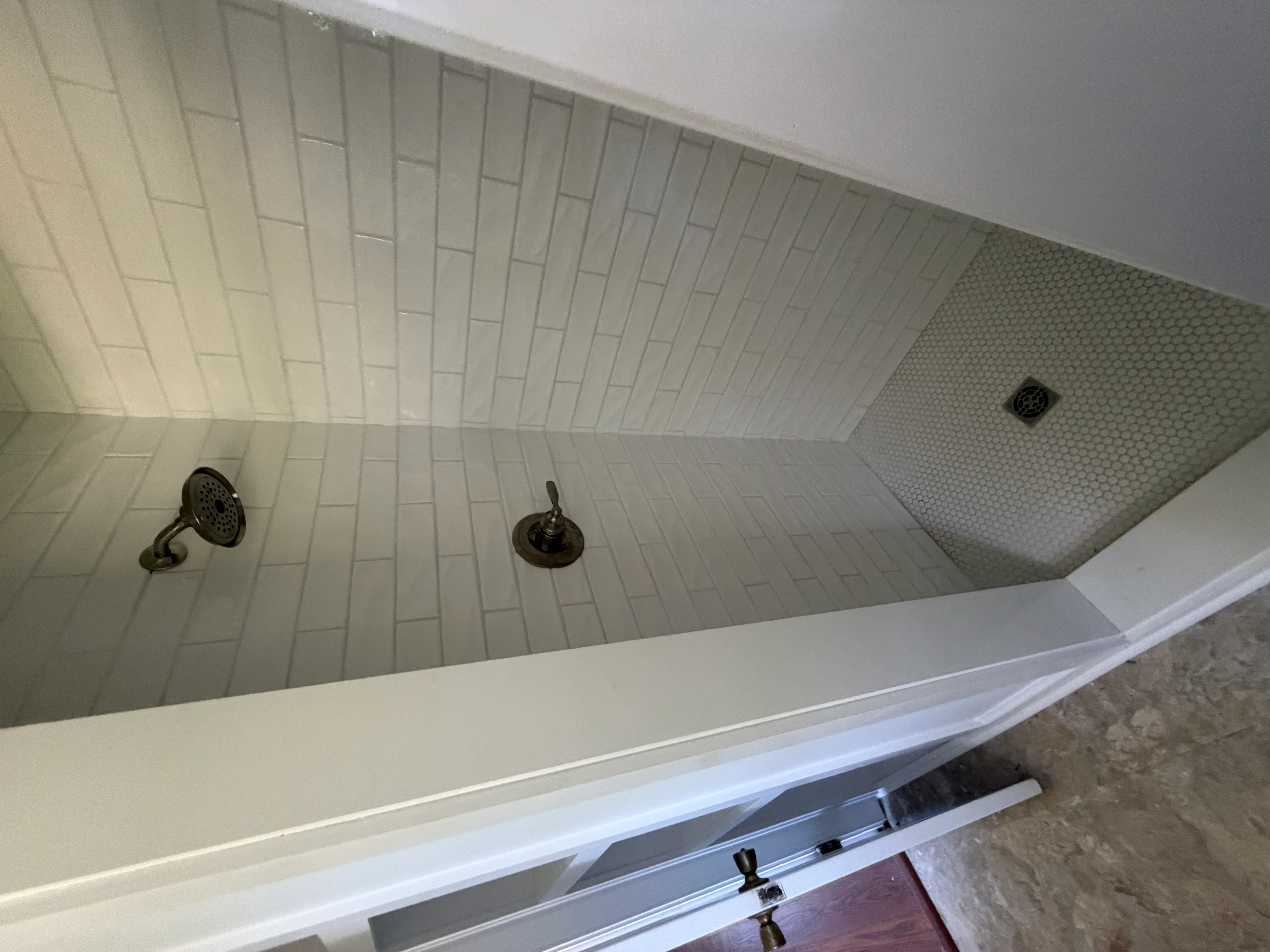 Shower interior with subway tile walls, dual bronze showerheads, and textured ceiling panel